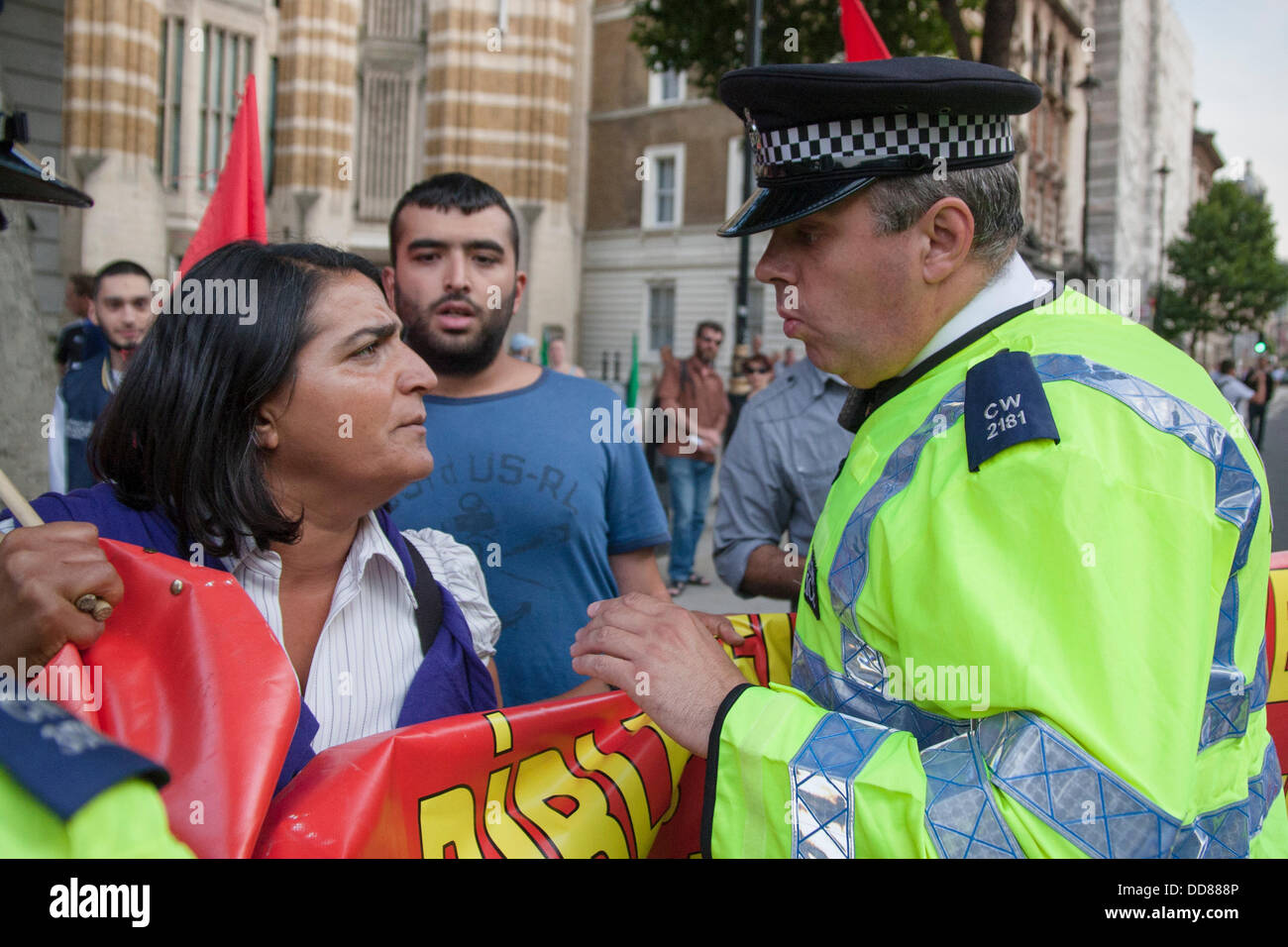 Londres, Royaume-Uni. Août 28, 2013. Un policier parle Turc de militants anti-guerre qu'ils arrivent à l'appui d'une protestation contre une possible intervention par le Royaume-Uni dans le cadre du conflit syrien à la suite des attaques d'armes chimiques, a imputé au régime Assad, sur les civils. Crédit : Paul Davey/Alamy Live News Banque D'Images