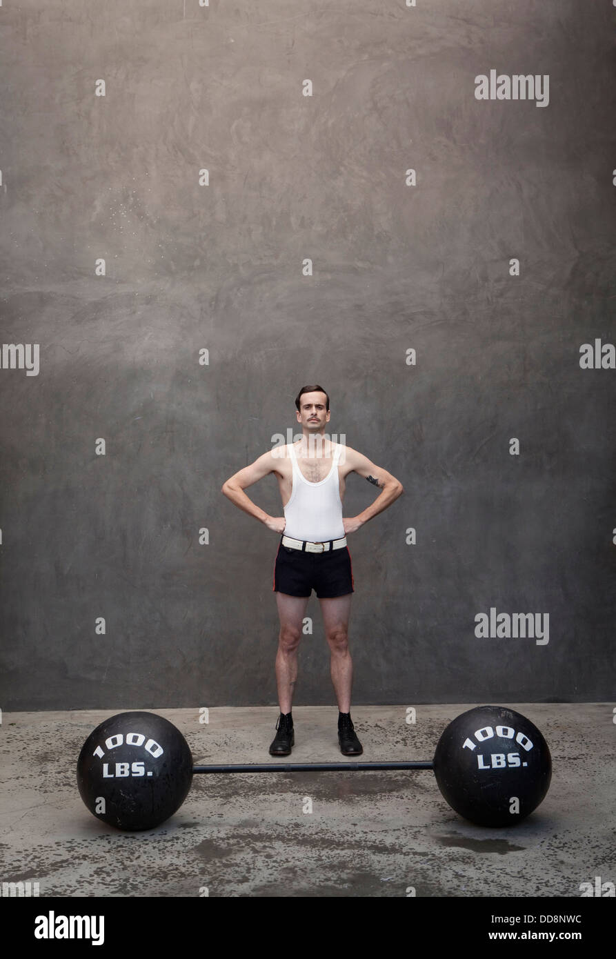 Skinny Caucasian weight lifter standing by haltères Banque D'Images
