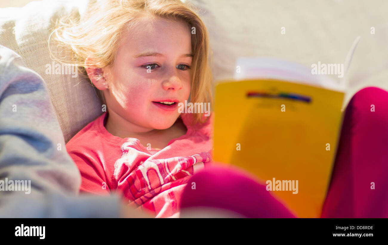 Caucasian girl reading on sofa Banque D'Images