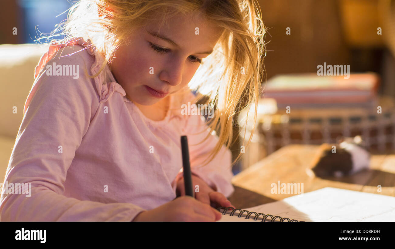 Caucasian girl doing homework on desk Banque D'Images