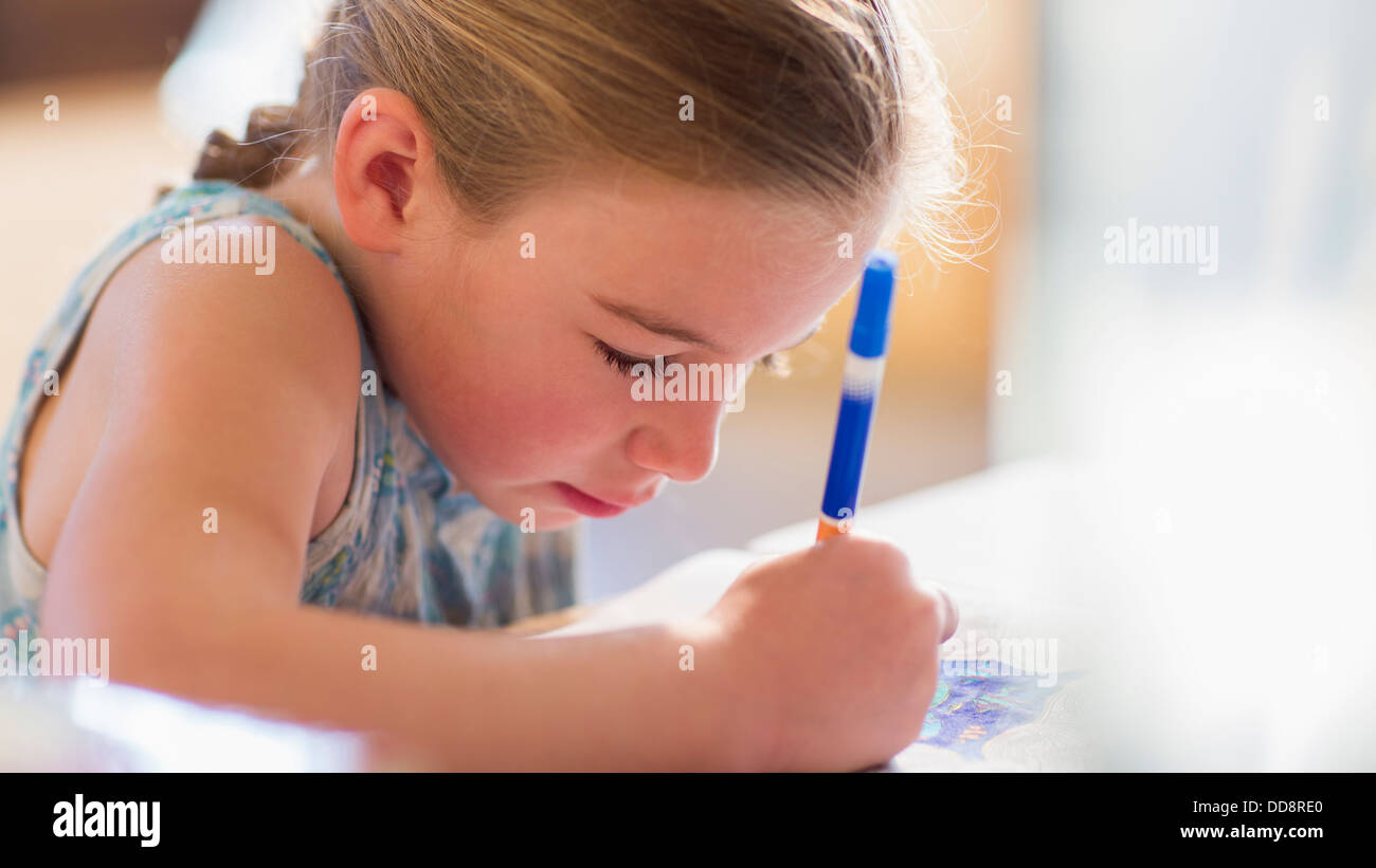 Caucasian girl coloring at table Banque D'Images