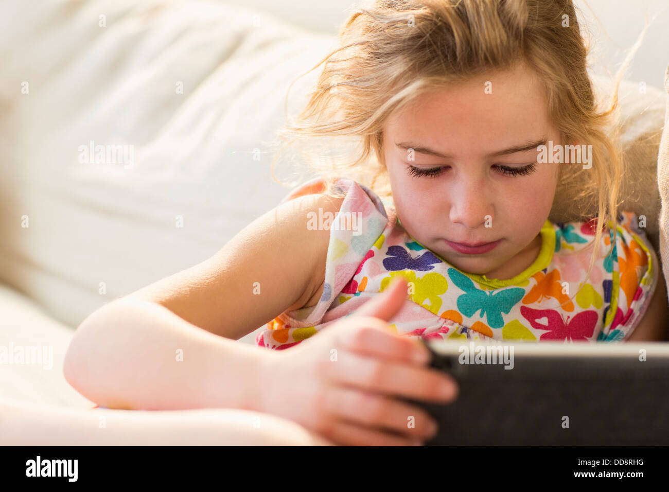 Caucasian girl using tablet computer on sofa Banque D'Images