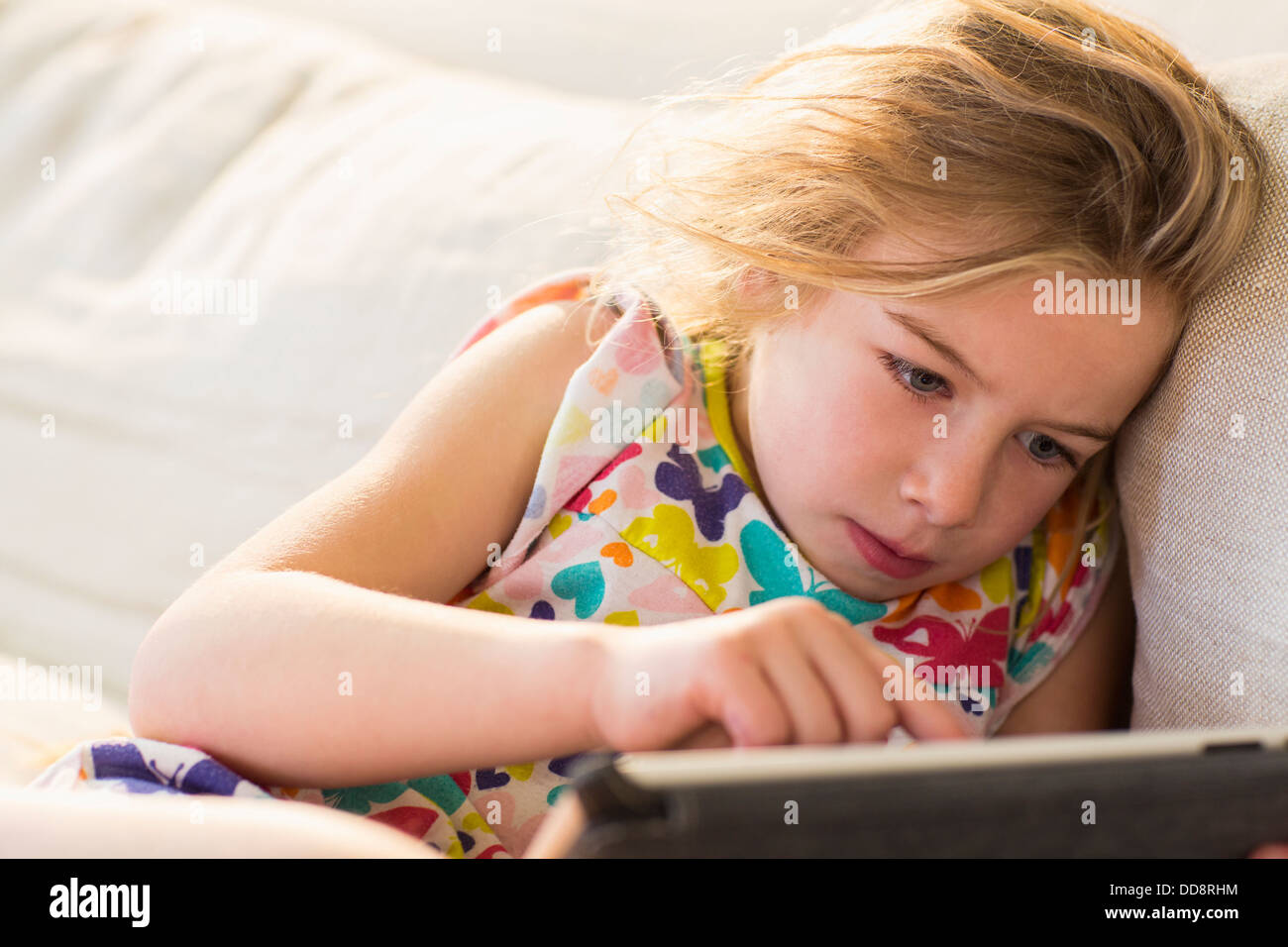 Caucasian girl using tablet computer on sofa Banque D'Images