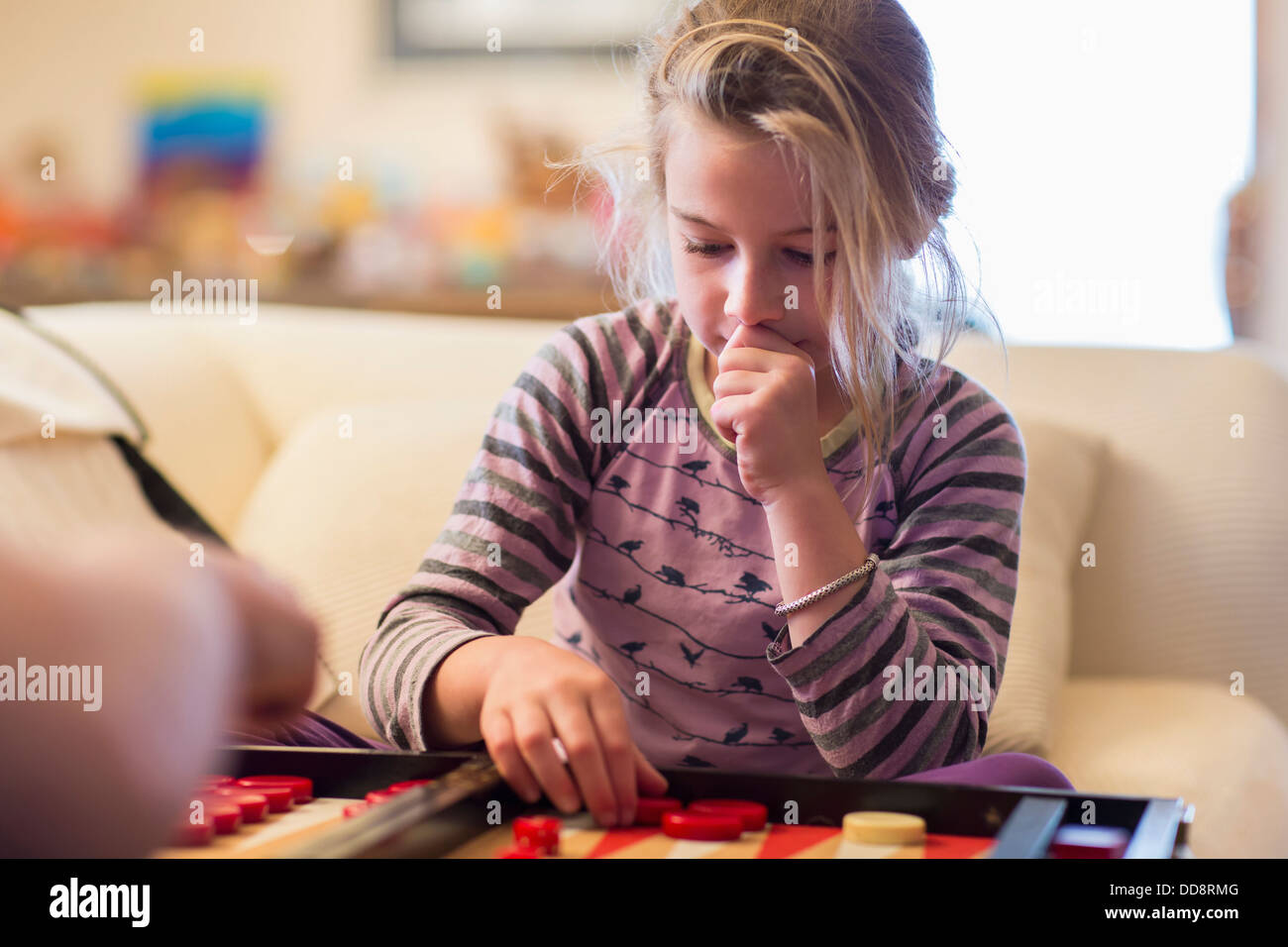 Caucasian girl jouant au backgammon sur canapé Banque D'Images