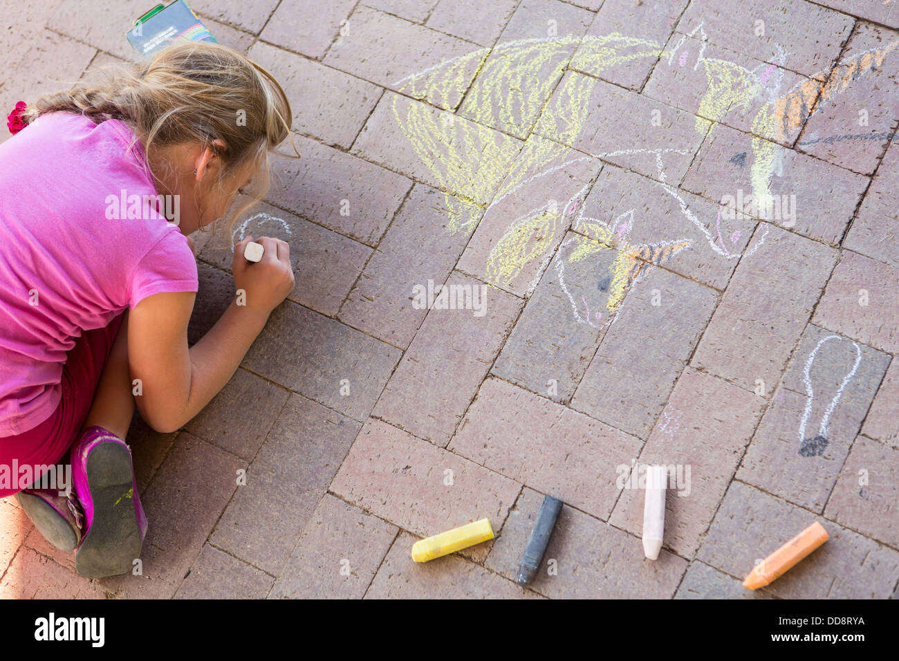 Caucasian girl dessin à la craie sur la brique Banque D'Images