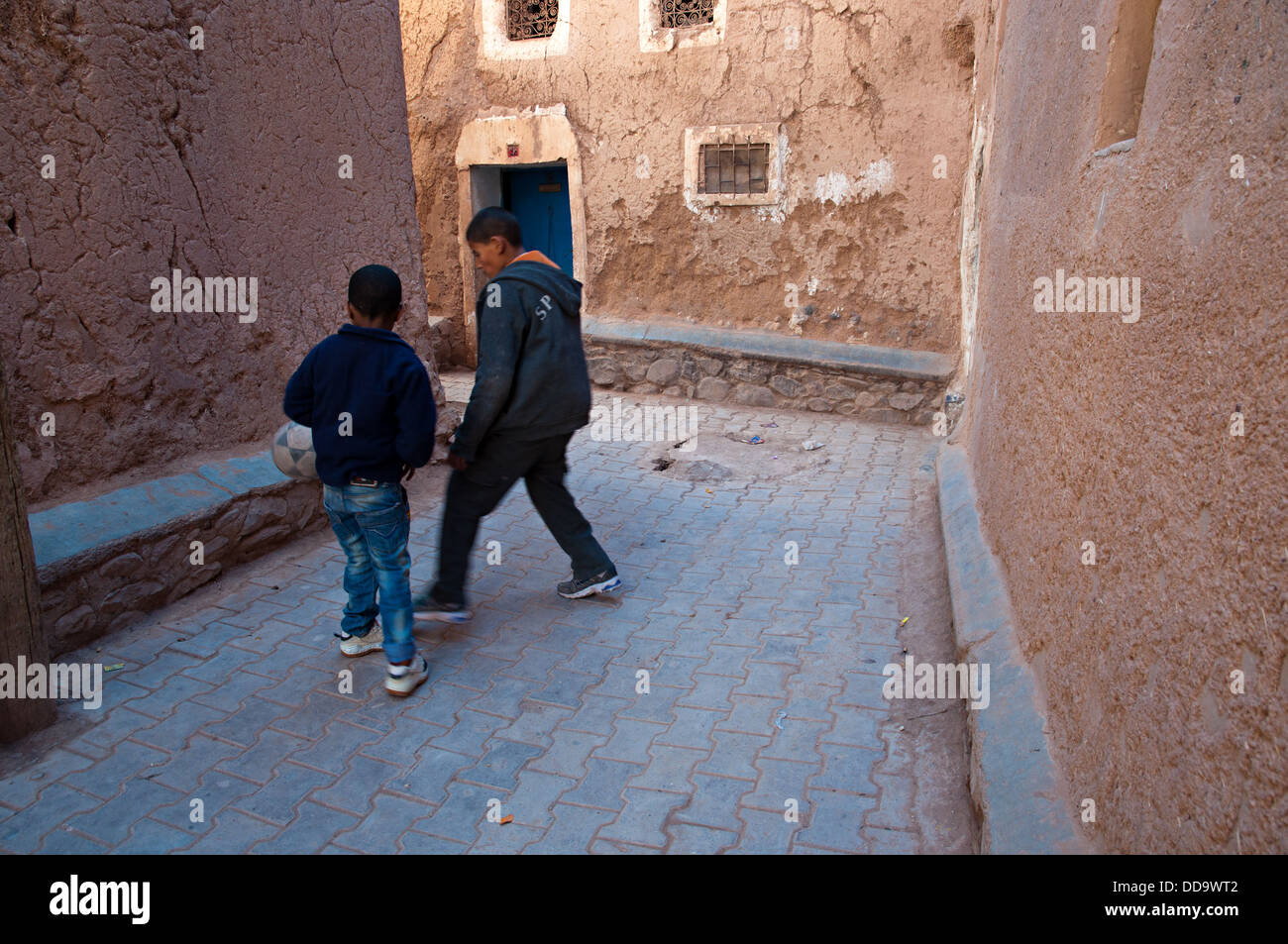 Deux enfants jouant au football dans les rues de la mellah (quartier juif), Ouarzazate, Maroc Banque D'Images