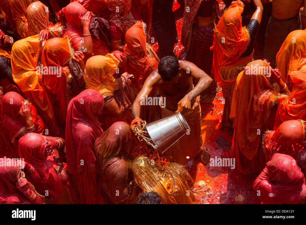 Un homme jette un seau d'eau pour les femmes dans une bataille symbolique lors de la fête de Holi dans Baldeo Banque D'Images