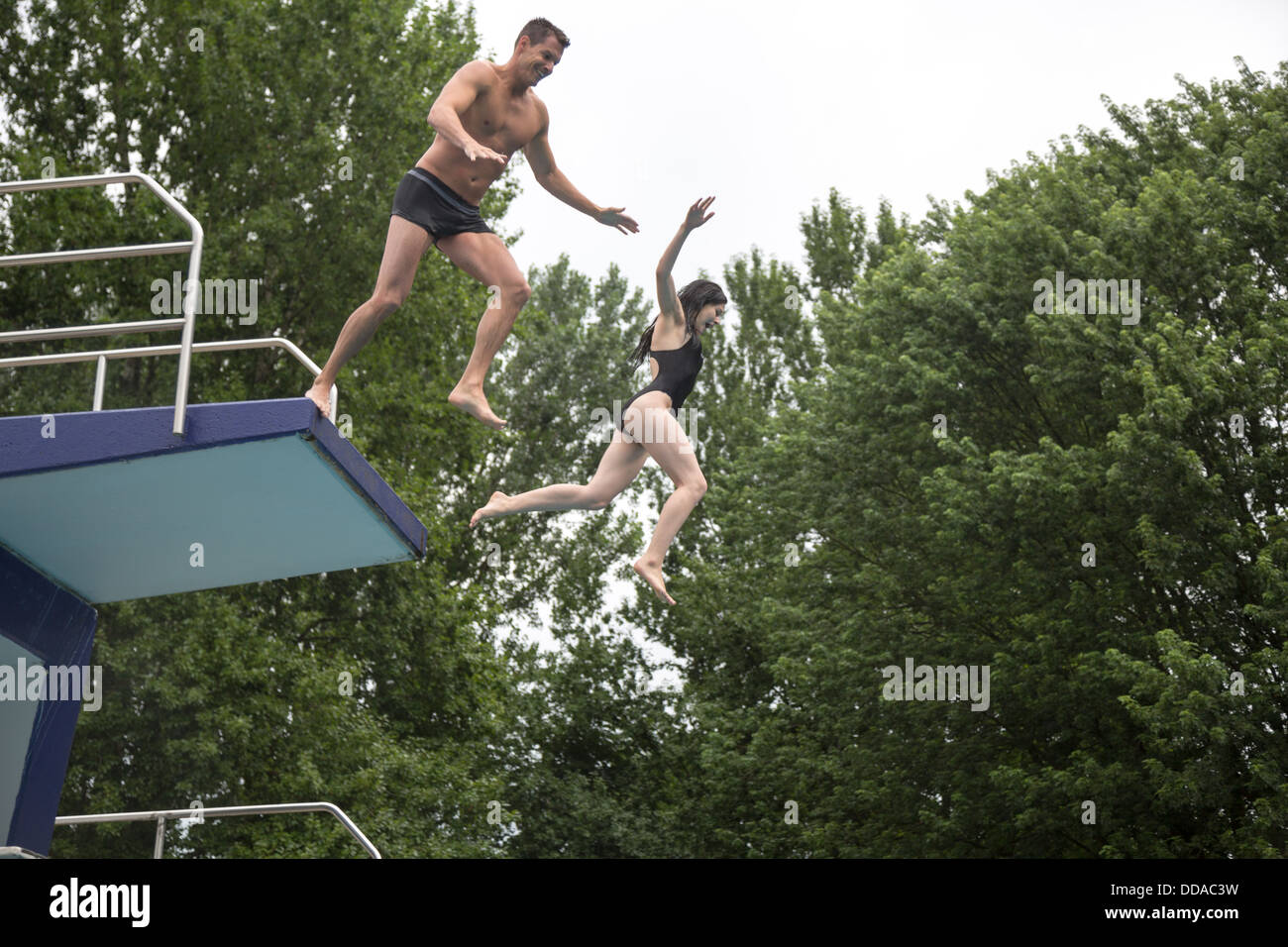 Un couple de sauter une plateforme de plongée dans une piscine publique Banque D'Images