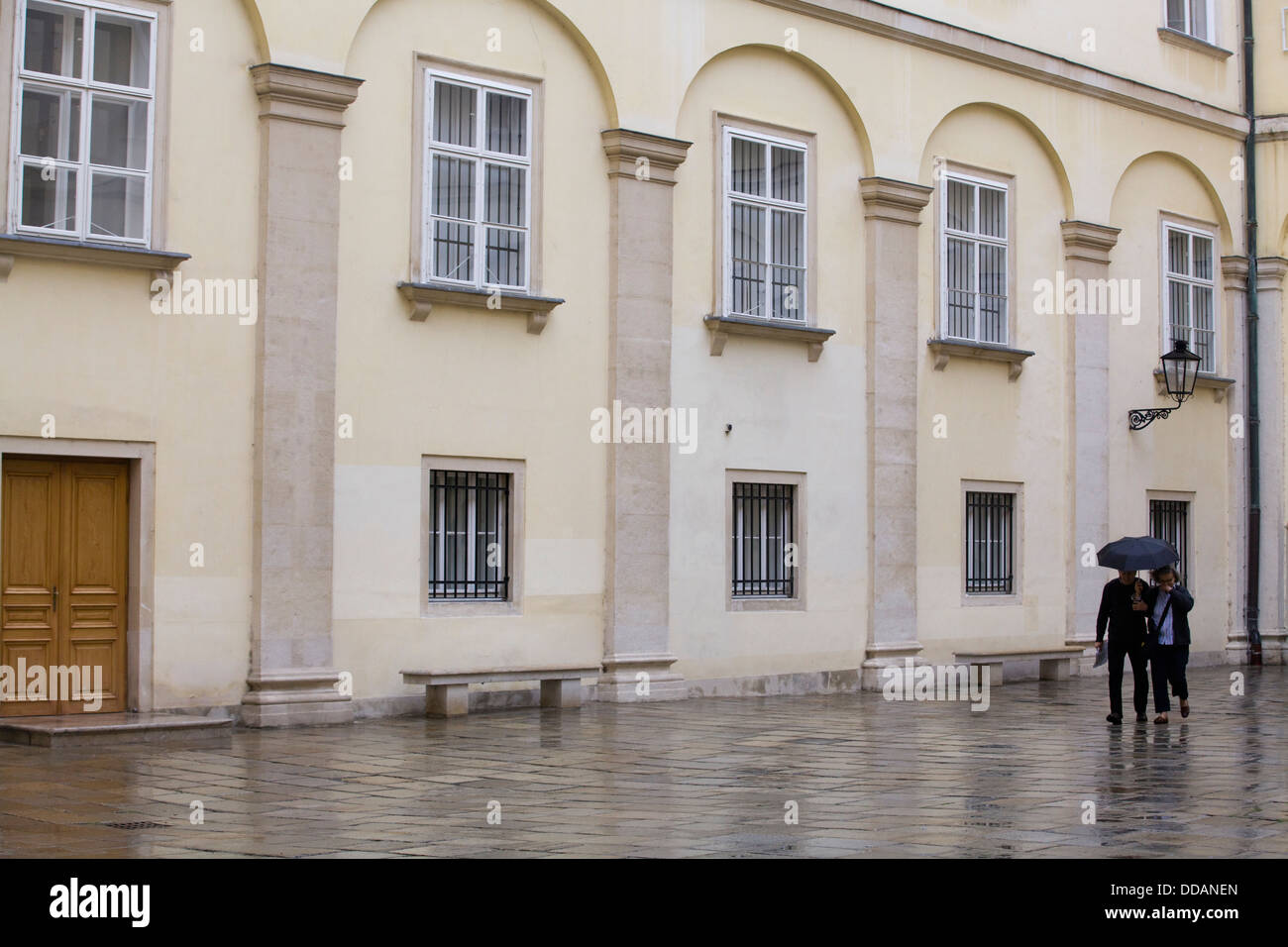 Couple en train de marcher sous la pluie à côté de l'école espagnole d'équitation Vienne Autriche Banque D'Images