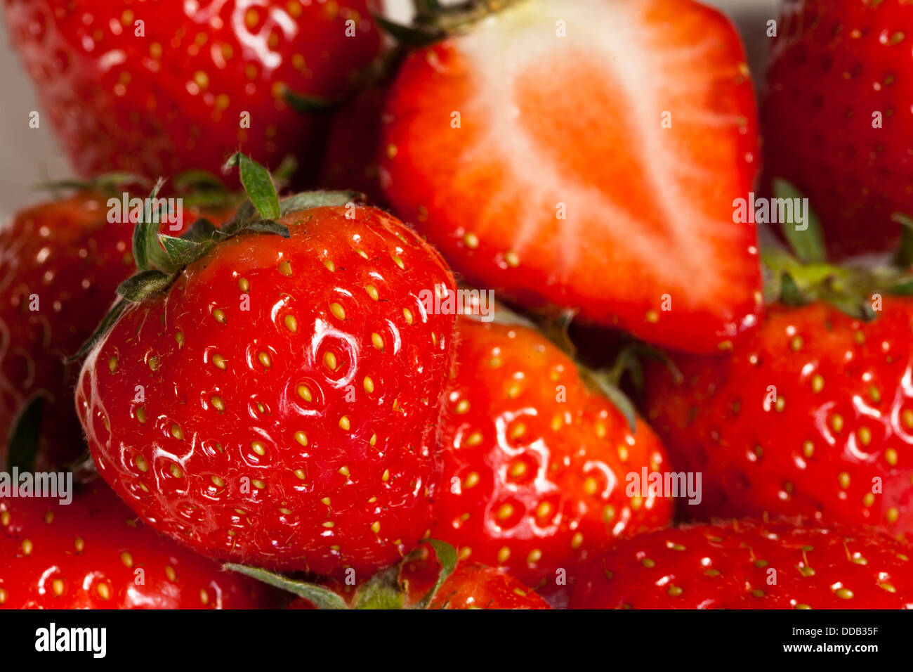 Juteux, doux, venu fraises entières et coupées en deux les fraises dans un bol Banque D'Images