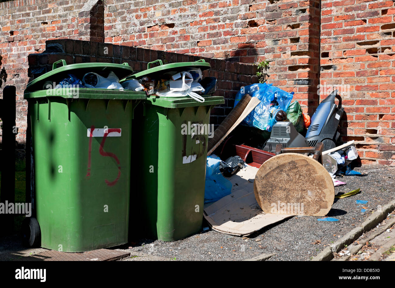 Plein débordement ménager vert déchets poubelles à roulettes poubelle et mouche basculant Tipped ordbish mess Angleterre Royaume-Uni GB Grande-Bretagne Banque D'Images