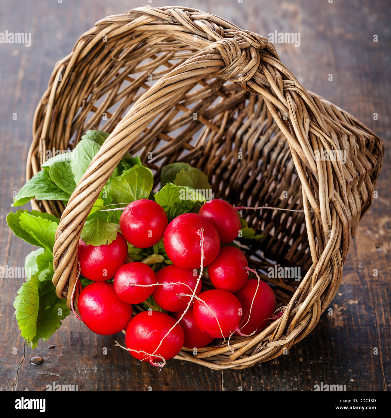 Frais jardin radis dans panier en osier sur fond de bois Banque D'Images