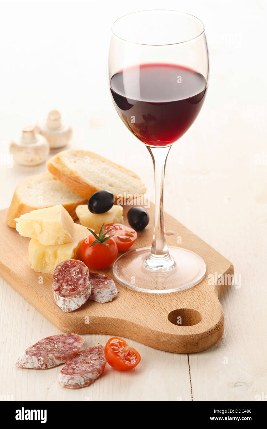 Verre à vin rouge et assortiment de fromages et fruits sur fond blanc Banque D'Images