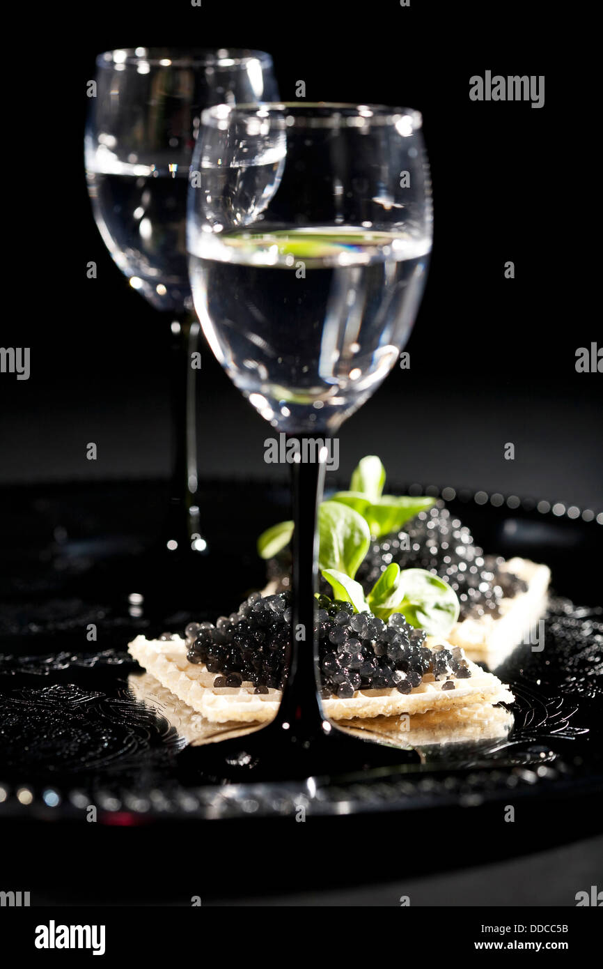 La vodka et les sandwiches avec caviar noir sur fond noir Banque D'Images