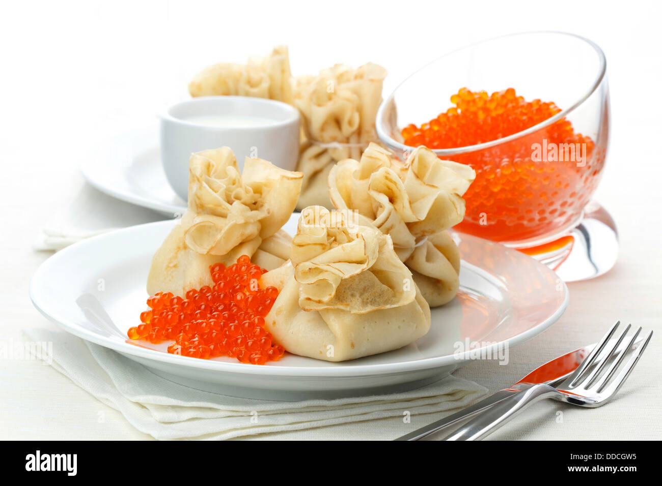 Sachets de crêpes avec du caviar rouge sur fond blanc Banque D'Images