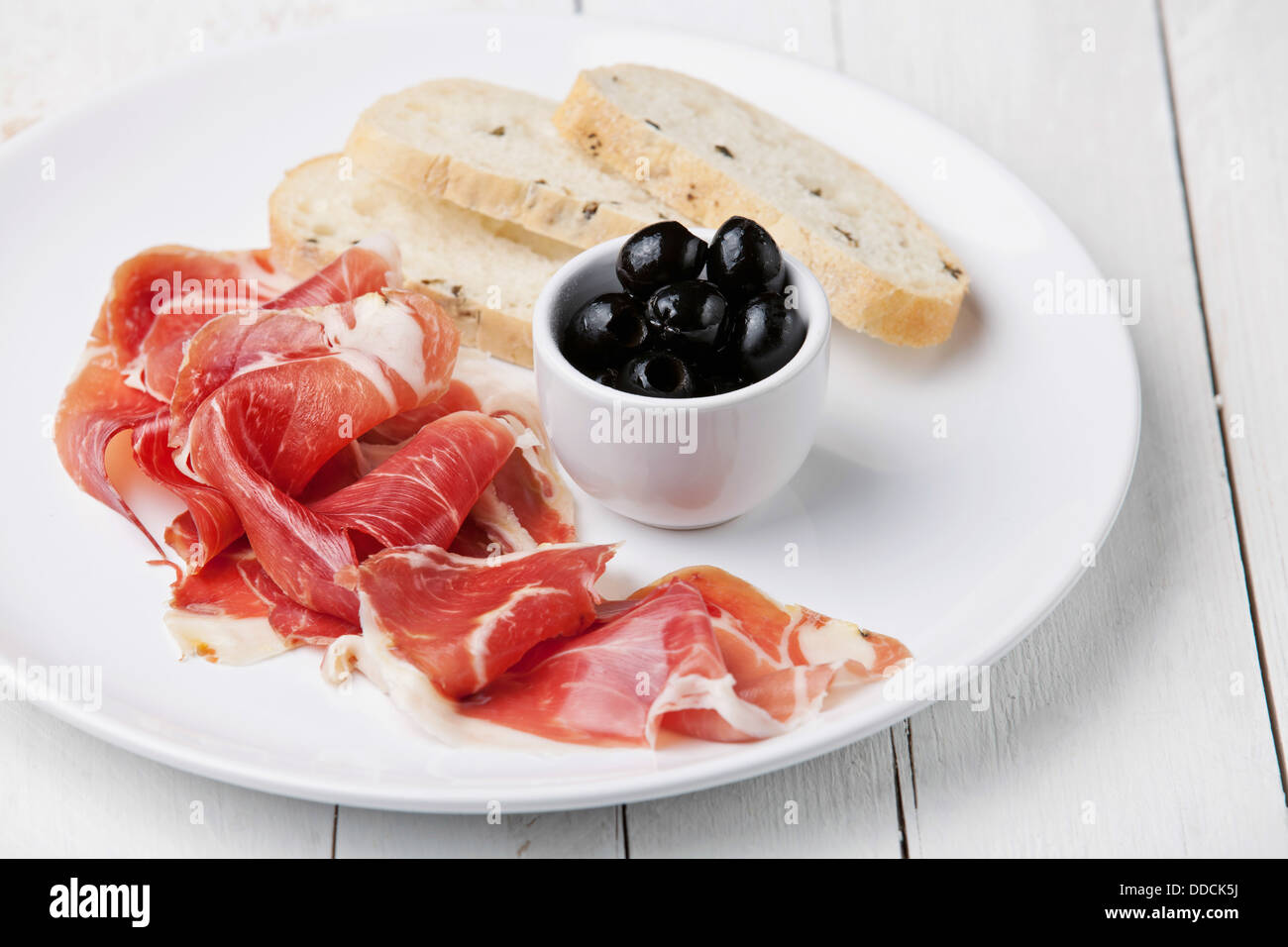 Tranches de jambon, olives noires et pain ciabatta on white plate Banque D'Images