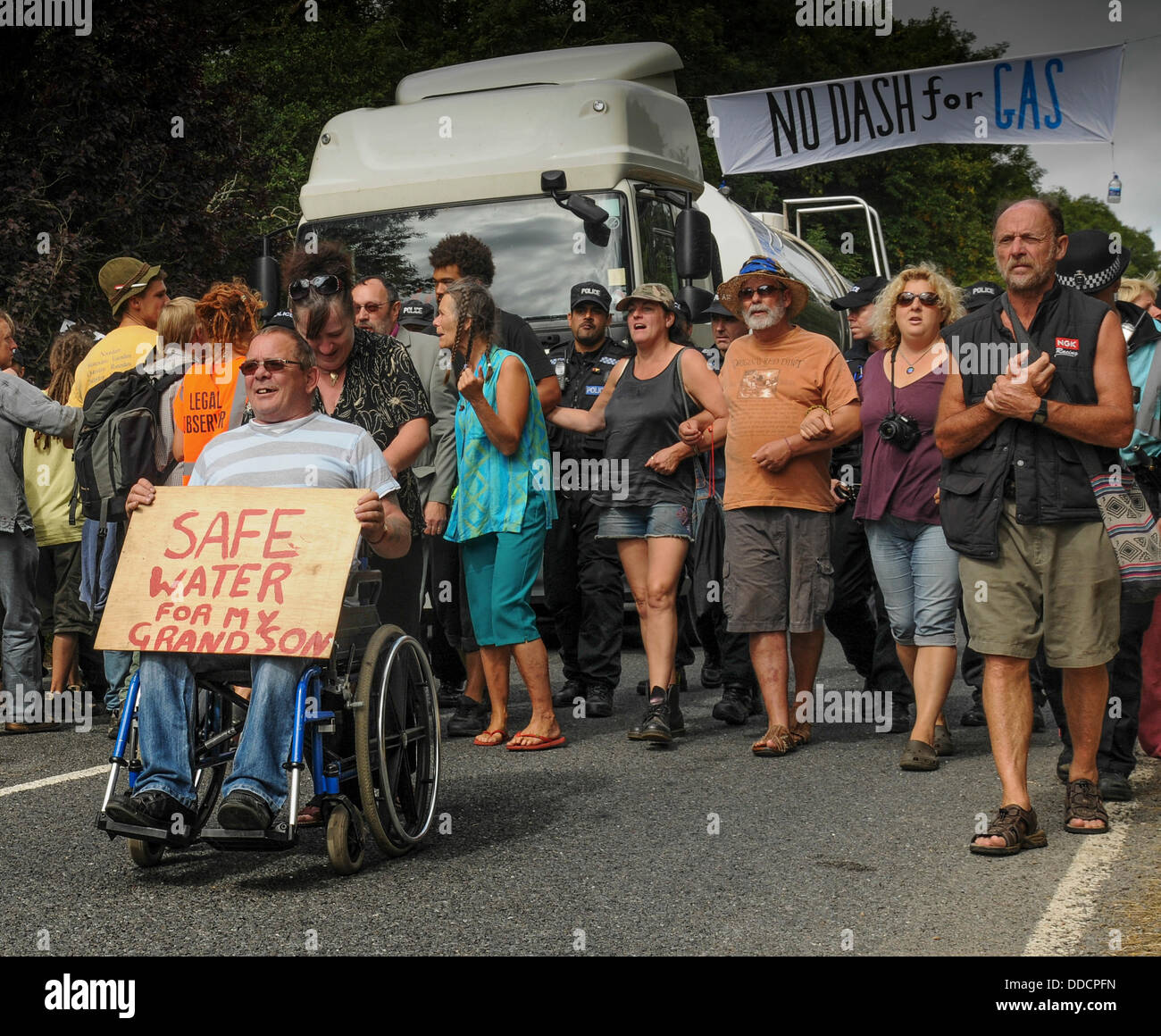 Balcombe, West Sussex, UK. Août 30, 2013. Robin Bothwell,en fauteuil roulant, d'Eastbourne conduit les écologistes comme ils marchent lentement en avant du camion de police escorté à Cuadrilla entrée du site. Presque une atmosphère de carnaval avec des messages très sérieux. Les militants anti fracturation protestent contre les forages d'essai par Cuadrilla sur le site de West Sussex qui pourraient mener à la fracturation hydraulique. Camp de la route continue de croître. © David Burr/Alamy Live News Banque D'Images