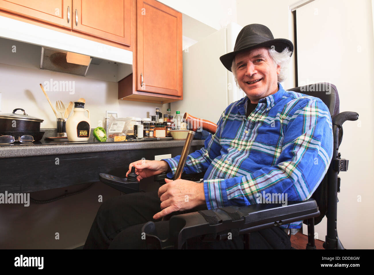 L'homme avec la sclérose en plaques en fauteuil roulant assis dans sa cuisine accessible Banque D'Images