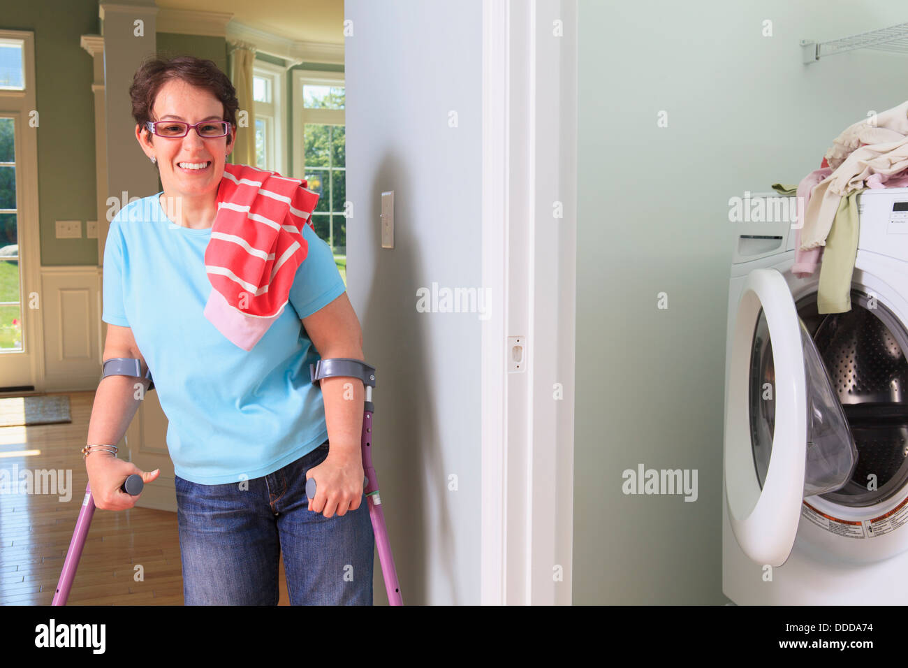 Femme avec la paralysie cérébrale qui lave des vêtements dans la buanderie et souriant Banque D'Images