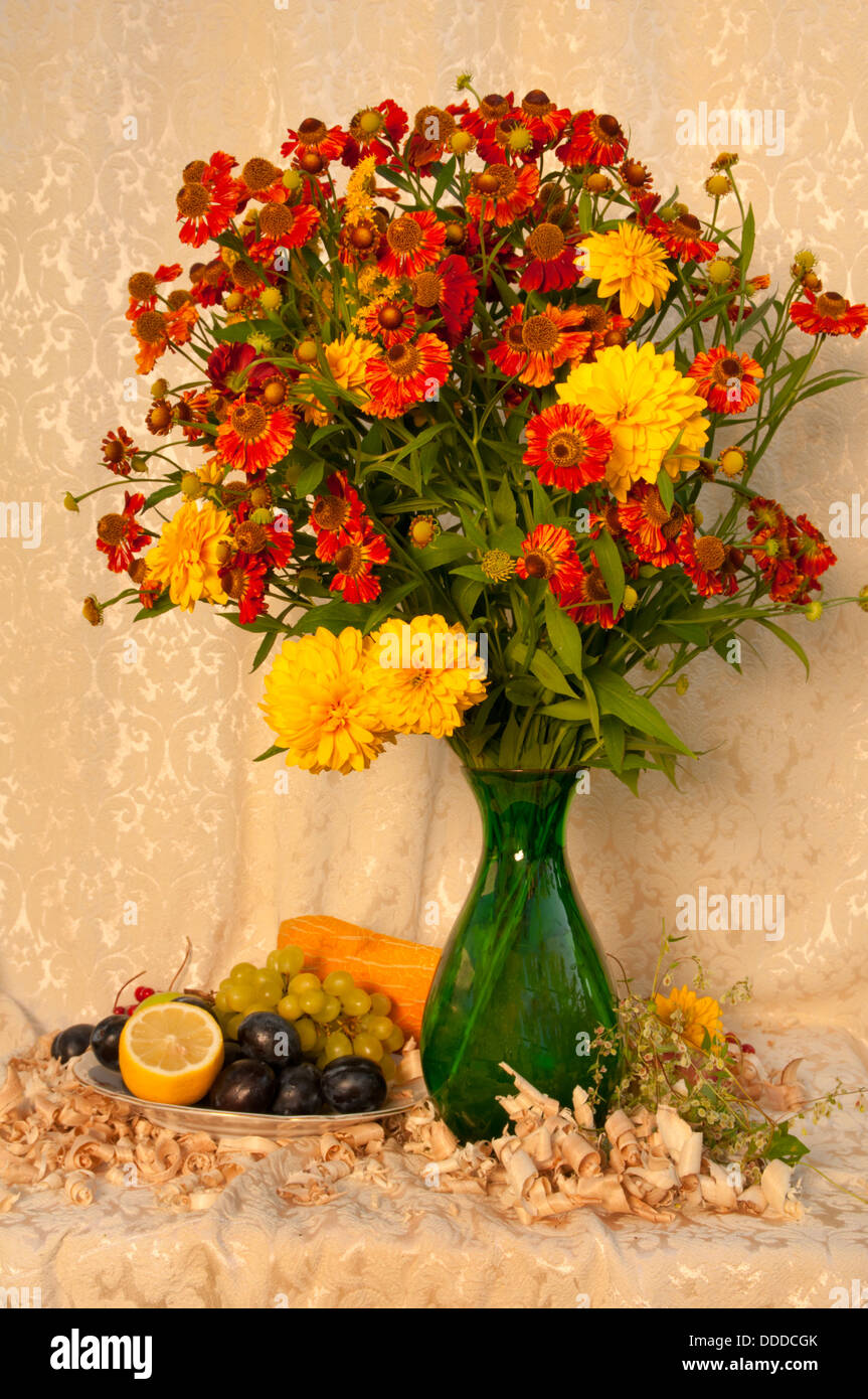Nature morte avec fleurs jaune vif et orange dans le vase vert avec des fruits Banque D'Images