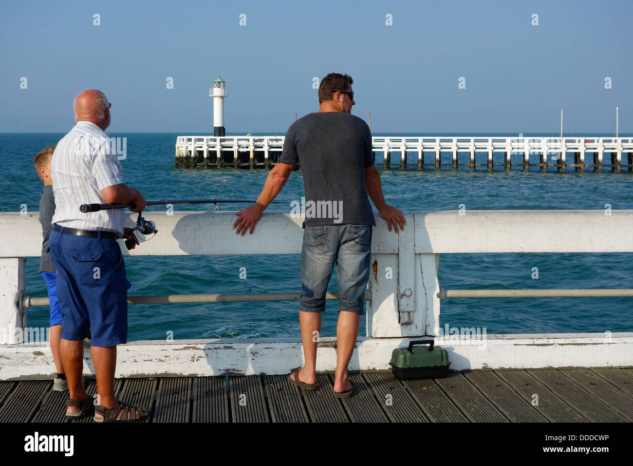 Fils, père et grand-père pêcher avec la canne à pêche de la jetée le long de la côte de la mer du Nord à Nieuport / Nieuport, Belgique Banque D'Images
