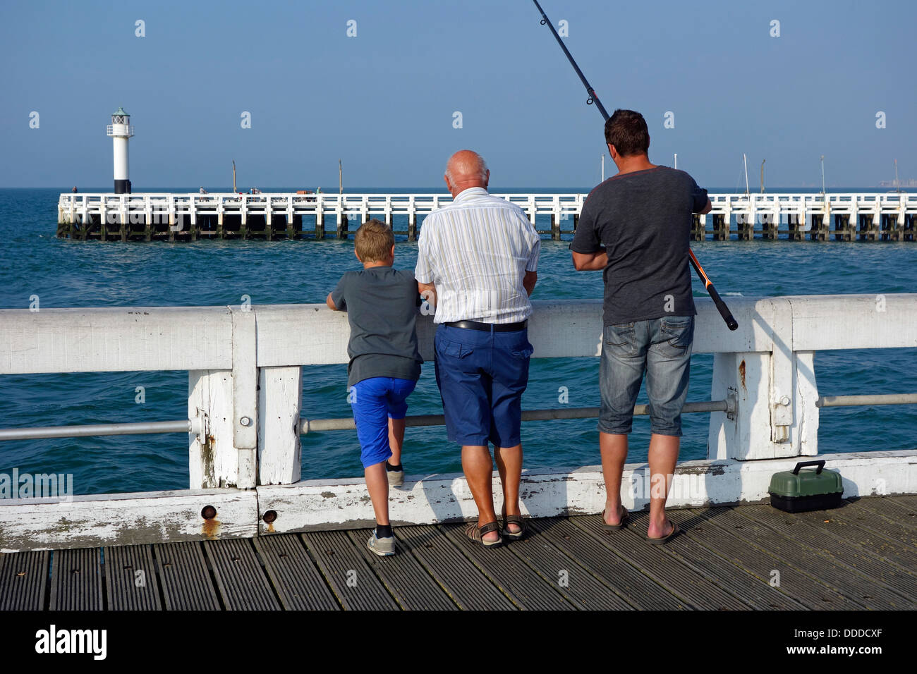 Fils, père et grand-père pêcher avec la canne à pêche de la jetée le long de la côte de la mer du Nord à Nieuport / Nieuport, Belgique Banque D'Images