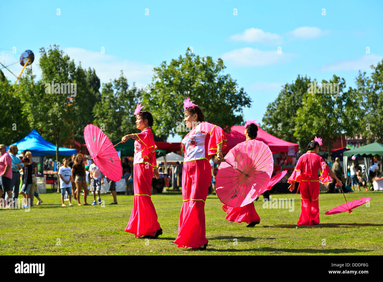 Spectateurs regardant que quatre femmes exécuter une danse chinoise à l'organisme de bienfaisance Dragon Boat Festival d'été de défi, St Neots, Cambridgeshire, Angleterre Banque D'Images