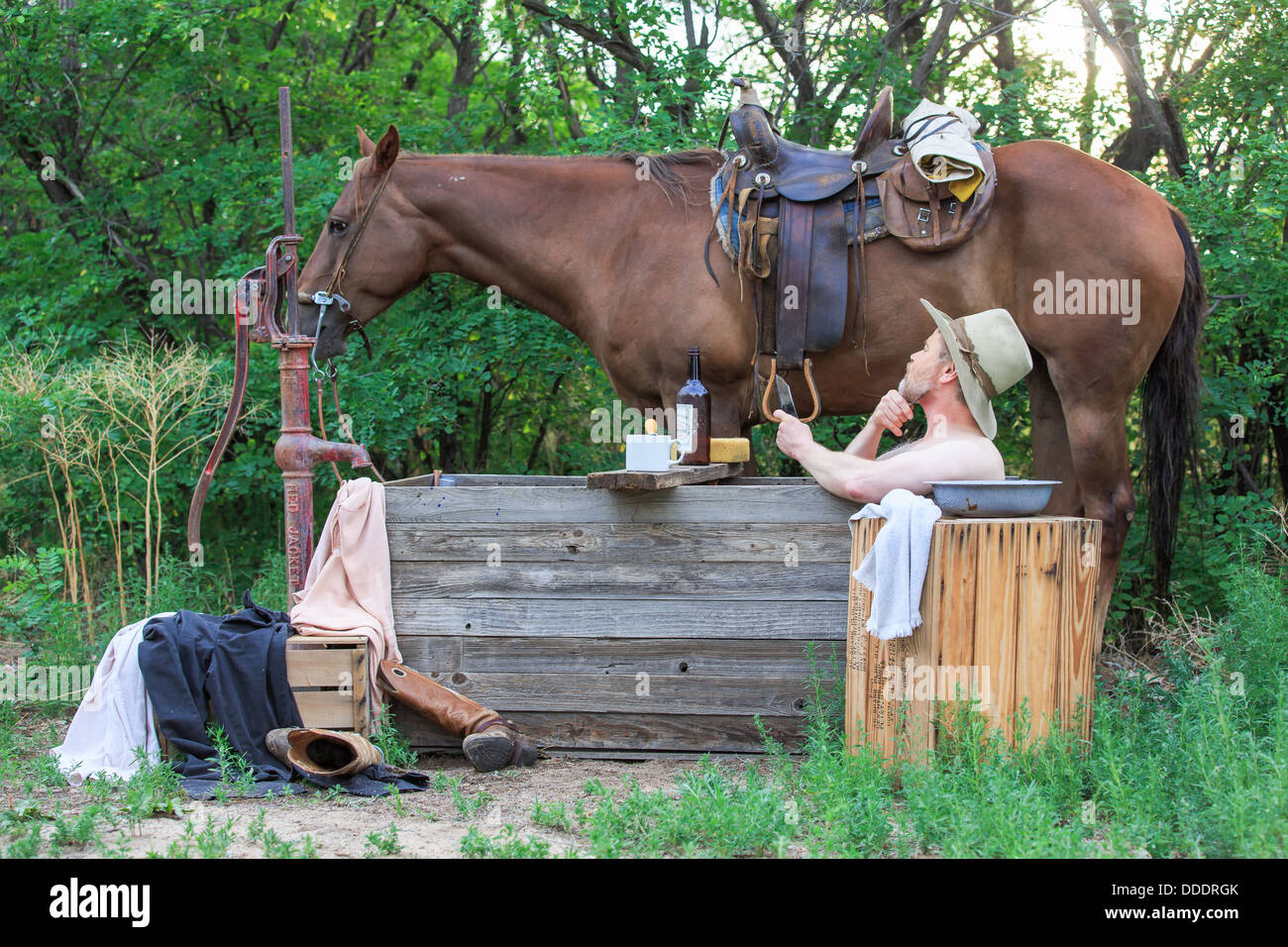 Un cowboy echelle et rasage le matin avec son cheval Banque D'Images