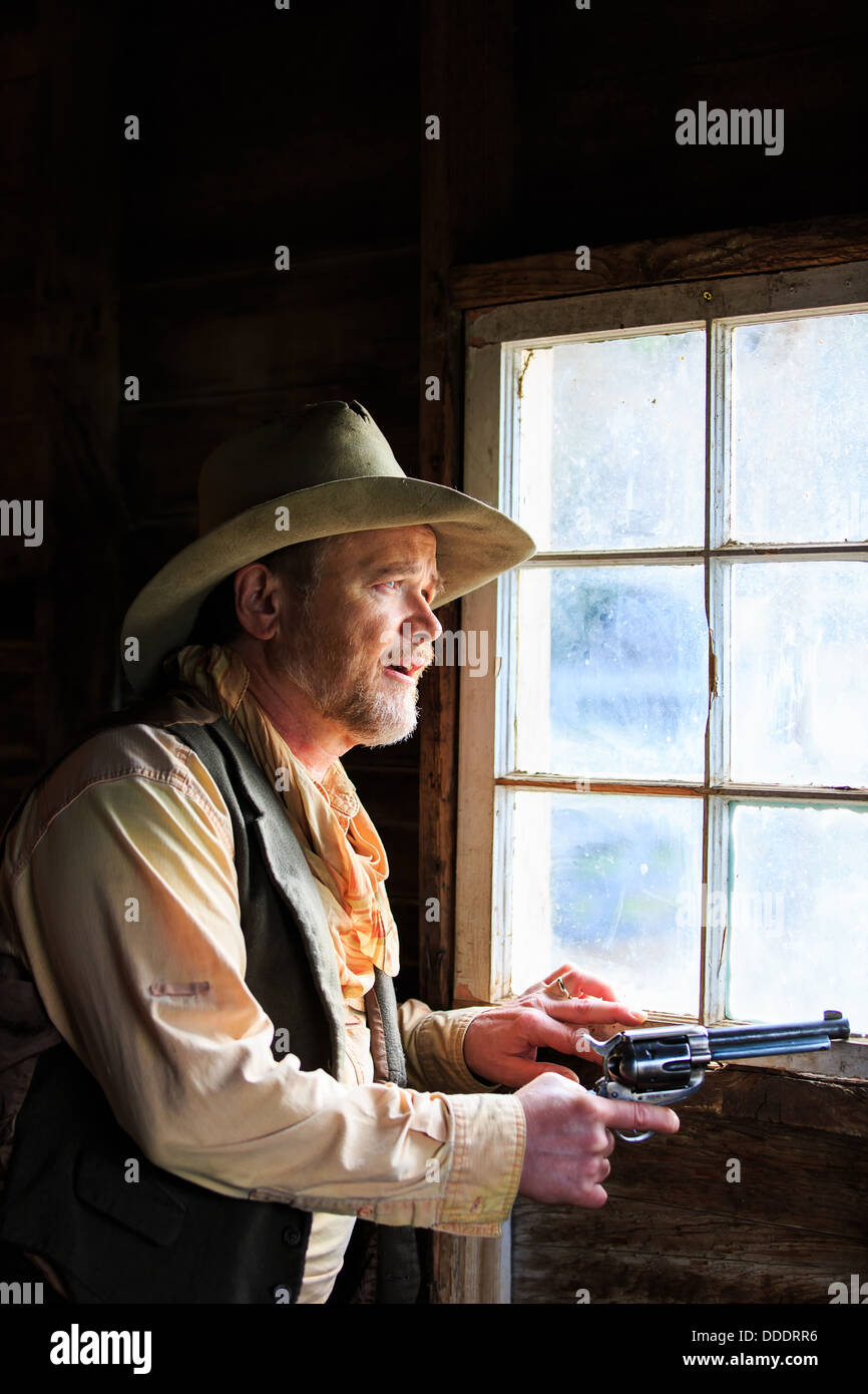 Un cowboy avec fusil tiré donne une fenêtre en prévision de danger Banque D'Images