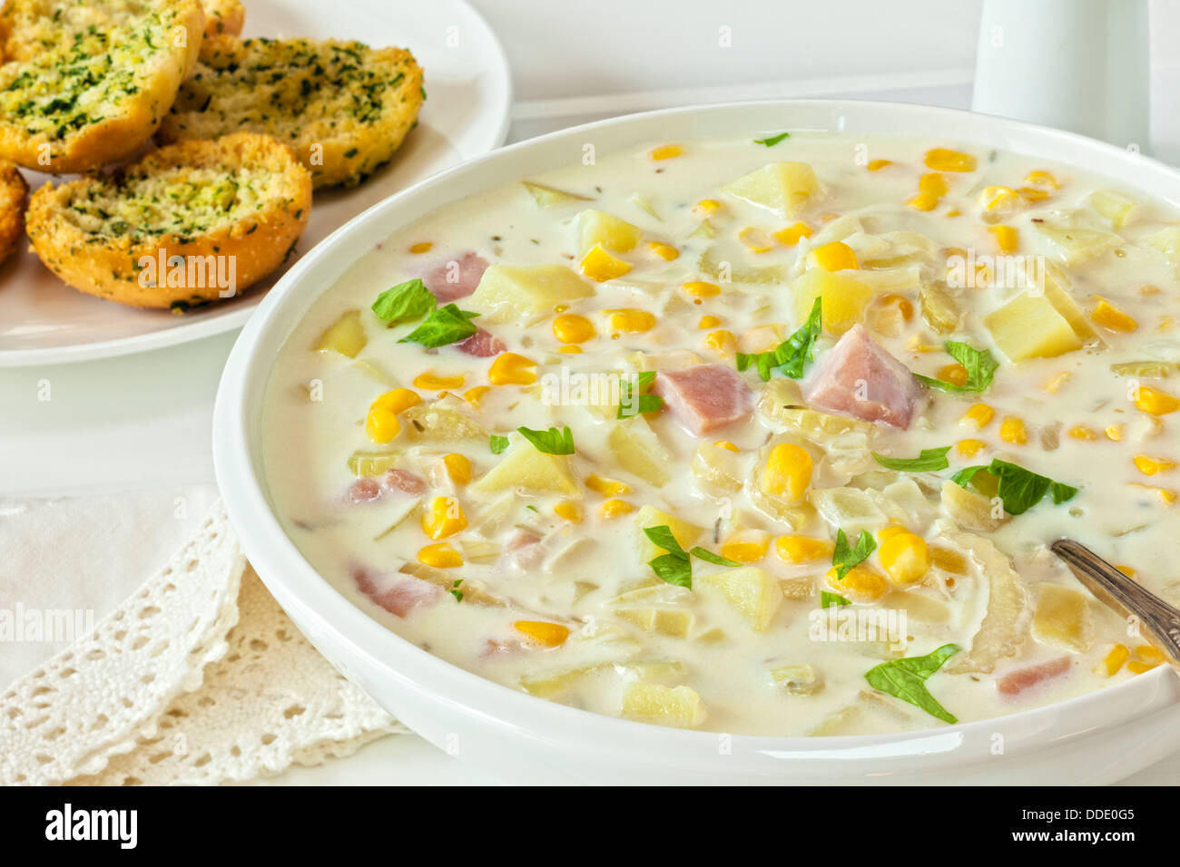 Chaudrée de maïs - Chaudrée de maïs crémeux au jambon et pommes de terre, servi avec du pain à l'ail croustillant. Banque D'Images