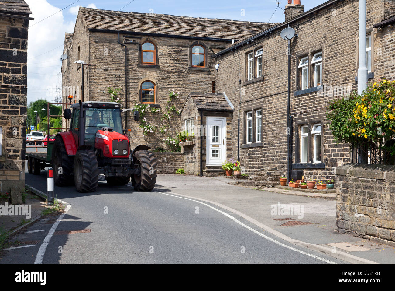 Tracteur agricole en passant par le centre du village, Barkisland, West Yorkshire Banque D'Images