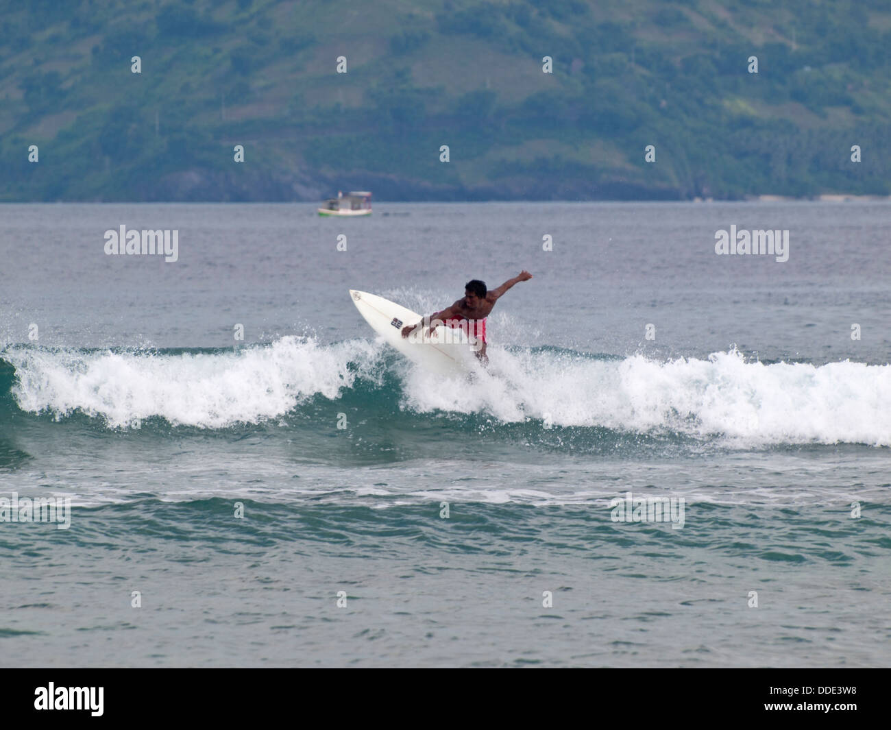 L'Indonésie n boy surf les vagues entre Lombok et Gili Trawangan Banque D'Images