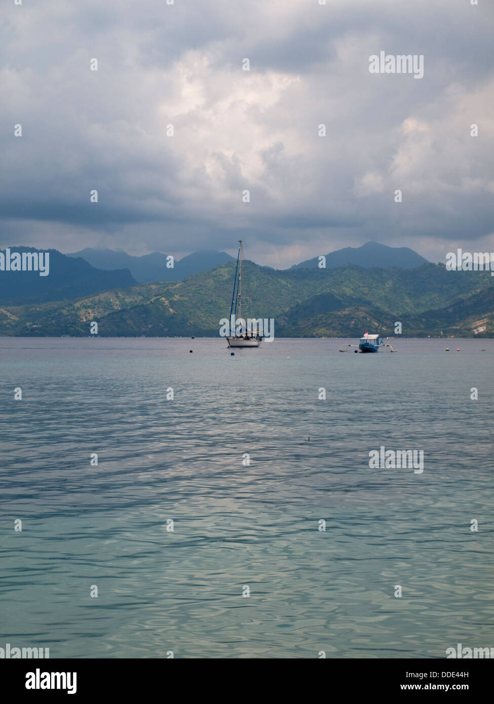 La mer tropicale avec des voiliers de l'île Lombok en arrière-plan et ciel nuageux Banque D'Images