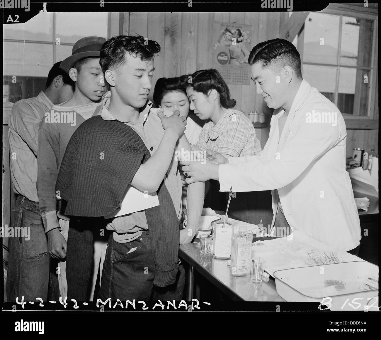 Cette photographie montre des nouveaux arrivants au Manzanar Relocation Center en Californie vaccinés par des infirmières évacuées, reflétant les efforts médicaux et de santé au sein du camp d'internement. Banque D'Images