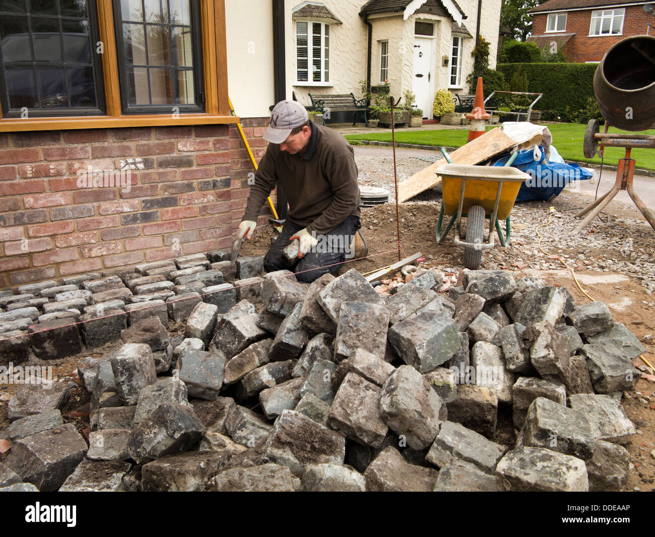 L bâtiment maison, disque de l'aménagement paysager, pose de pavés de granit récupérés workman autour de nouvelle construction d'accueil Banque D'Images