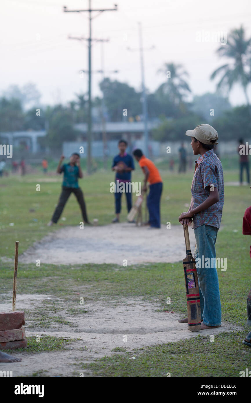 Les enfants jouer au cricket sur un champ au crépuscule dans le plateau Srimongol, zone de culture du Bangladesh Banque D'Images