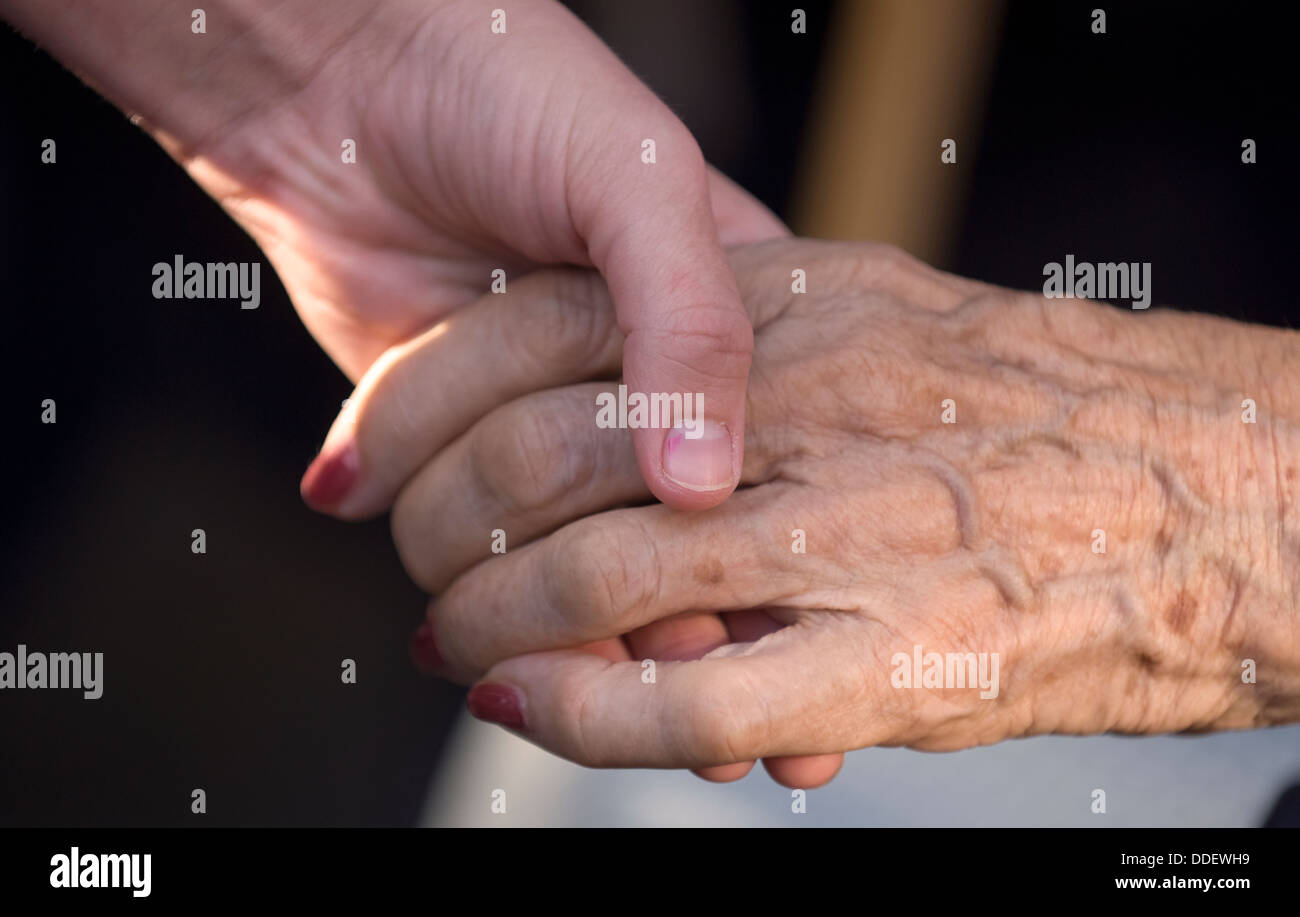 Jeune femme éducatrice holding hand de personnes âgées résidant à la maison pour les personnes atteintes de démence, Bordon, Hampshire, Royaume-Uni. Banque D'Images