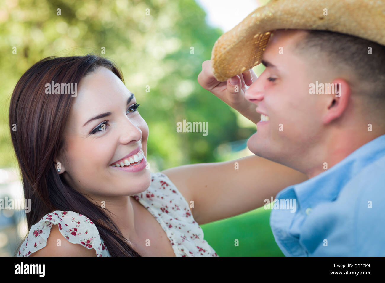 Happy Mixed Race couple romantique avec Cowboy Hat flirter dans le parc. Banque D'Images