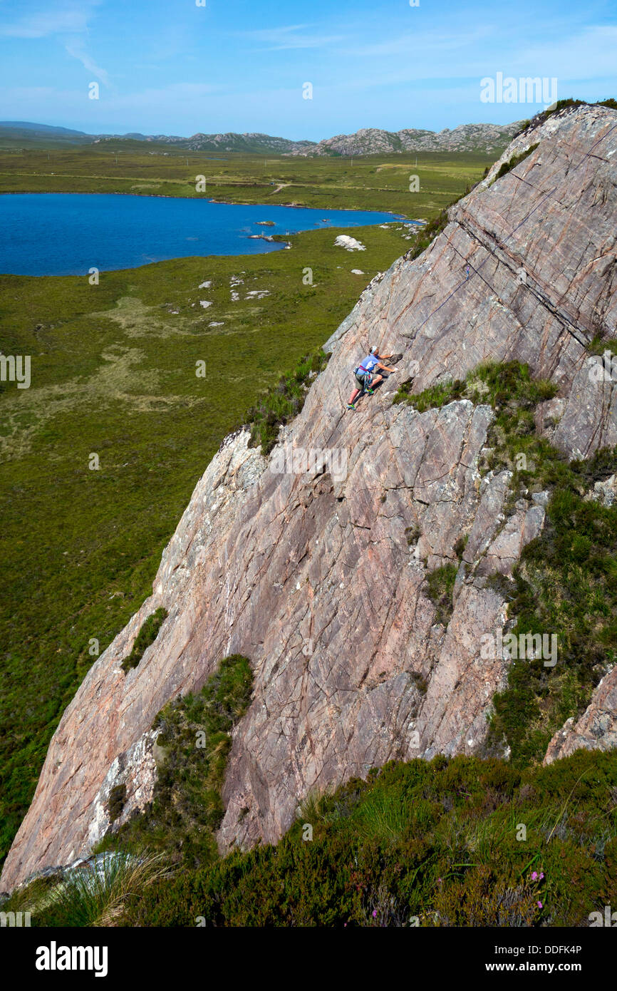 Rock climber sur dalle de grès avec ciel bleu et le lac, près de Gairloch, nord-ouest de l'Ecosse, Banque D'Images