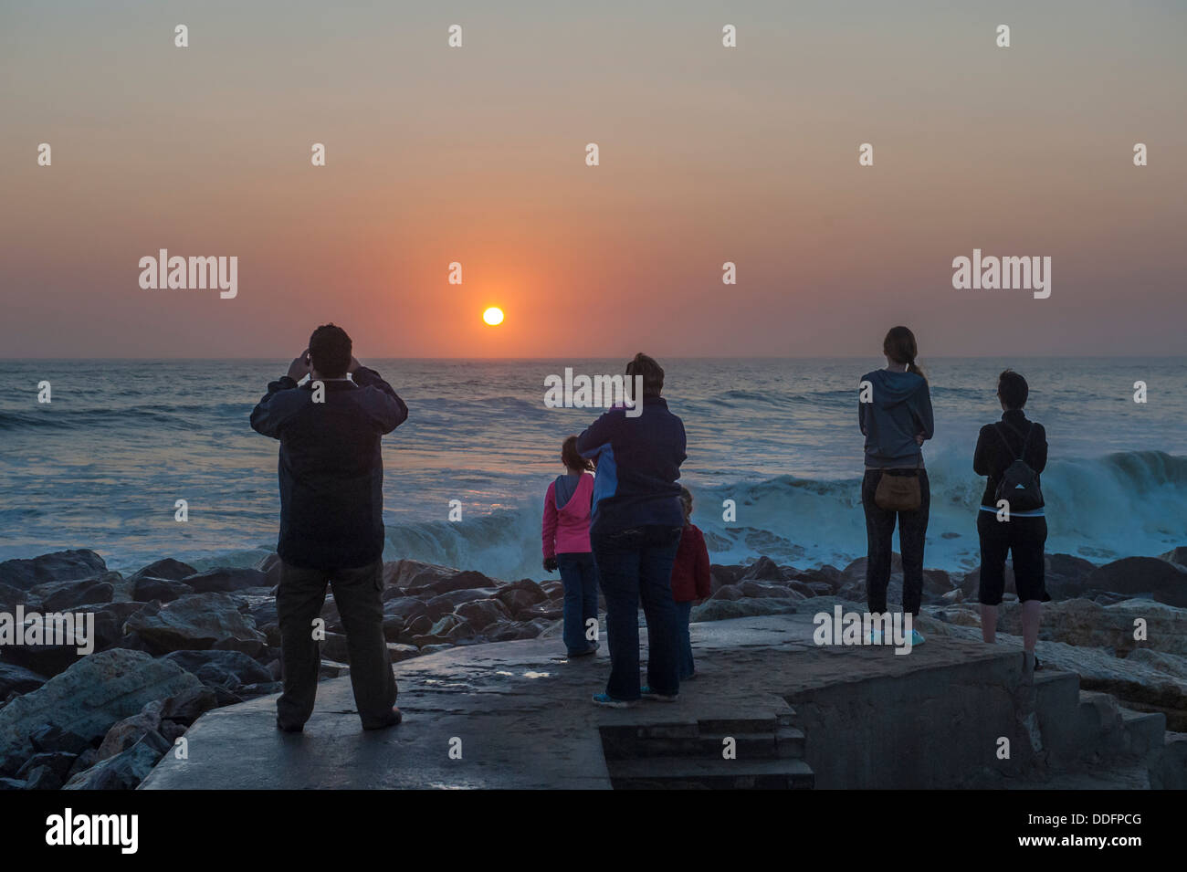 Une famille de montres et de photographies le coucher du soleil sur l'océan à Swakopmund, Namibie Banque D'Images