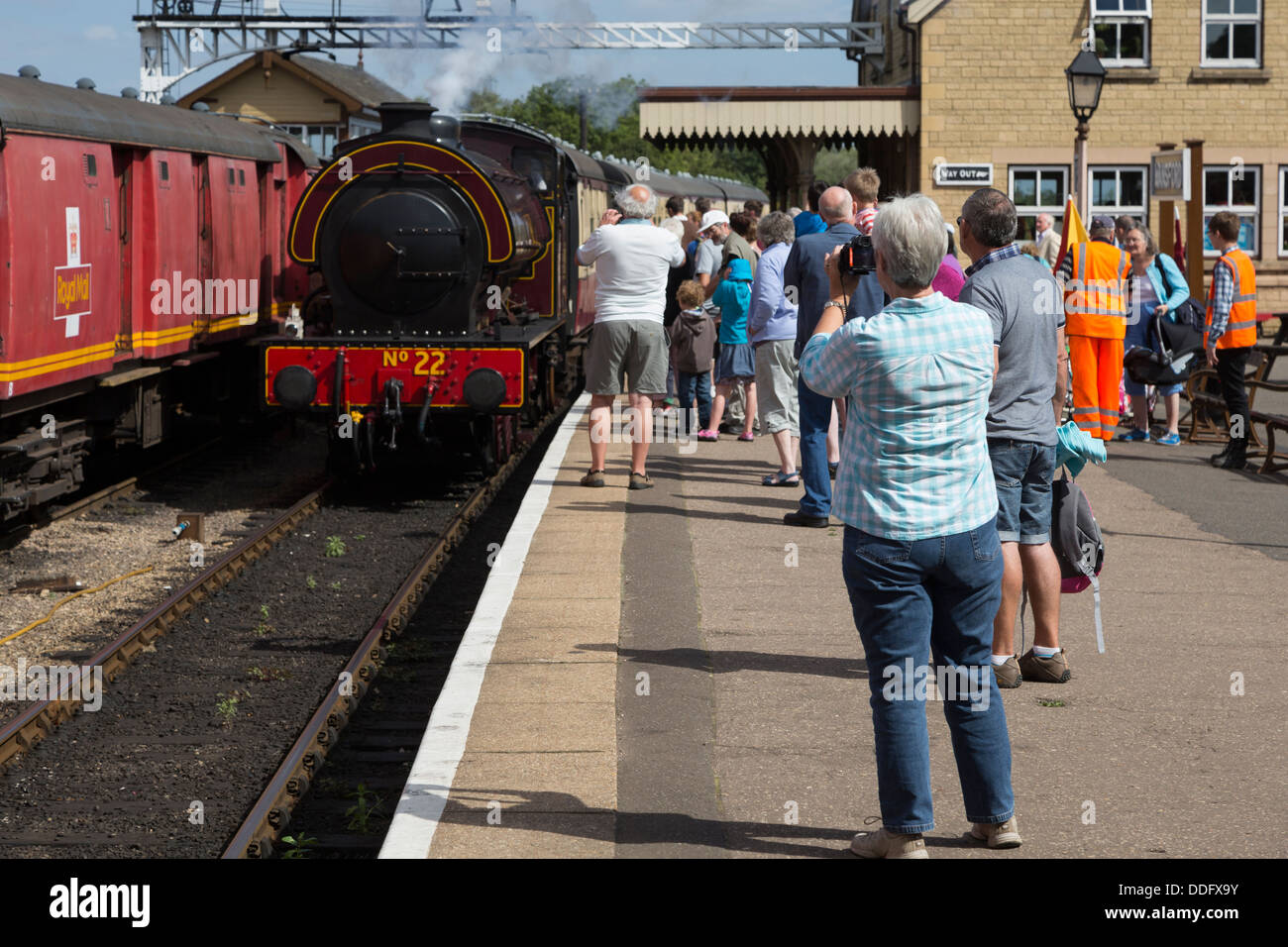 Regardez les amateurs de l'arrivée d'un train à vapeur sur la station Oundle Nene Valley Railway. Banque D'Images