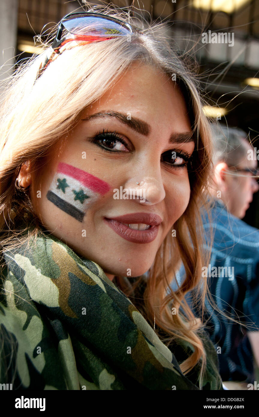 Manifestation contre toute intervention en Syrie. Une jeune femme blonde a un drapeau syrien sur sa joue et veste de camouflage Banque D'Images