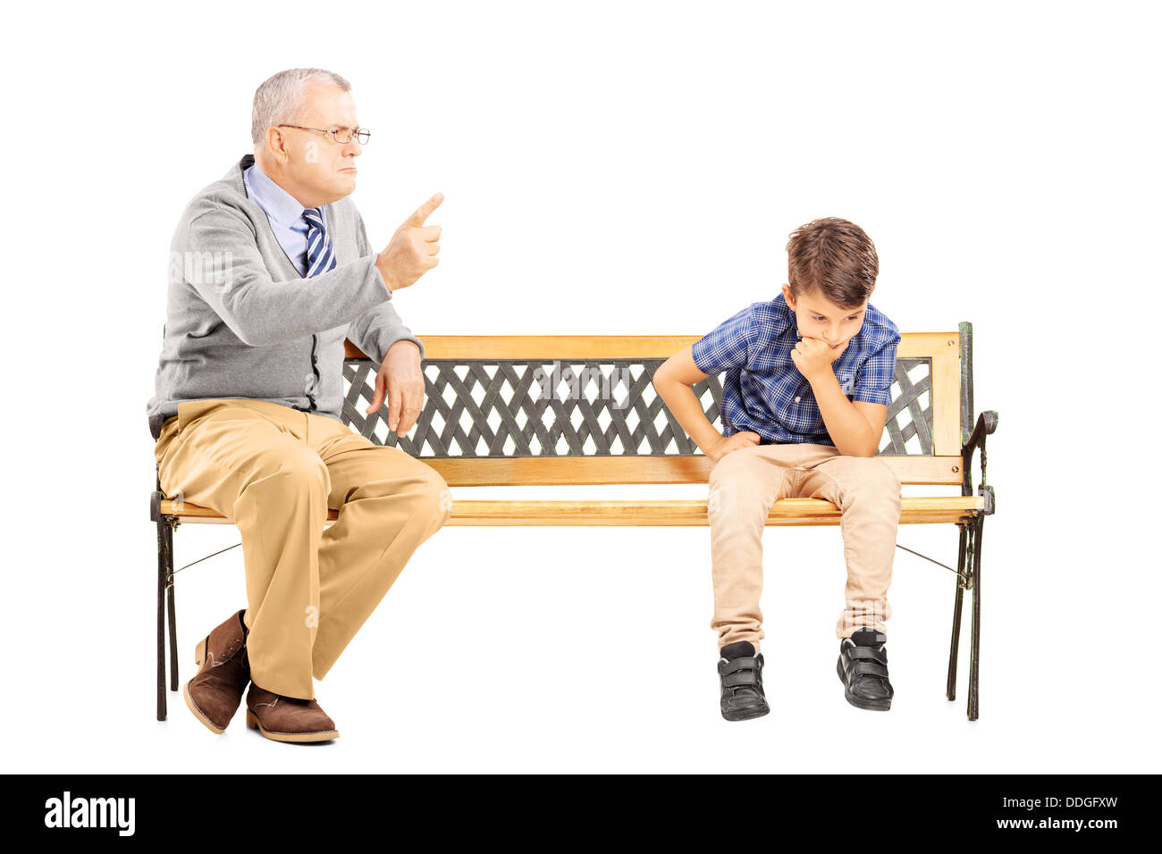 Grand-père en colère en criant à son neveu triste, assis sur un banc en bois Banque D'Images
