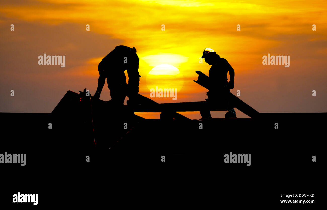 Les silhouettes des deux constructeurs construction contre un beau coucher du soleil Banque D'Images
