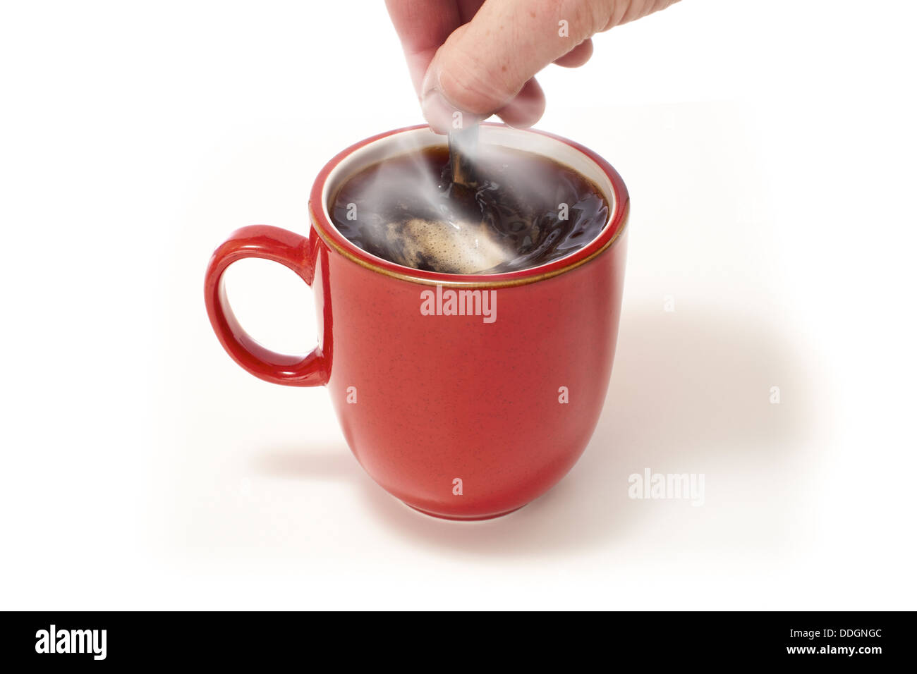 En remuant la main une tasse de café rouge sur un fond blanc isolé. Banque D'Images
