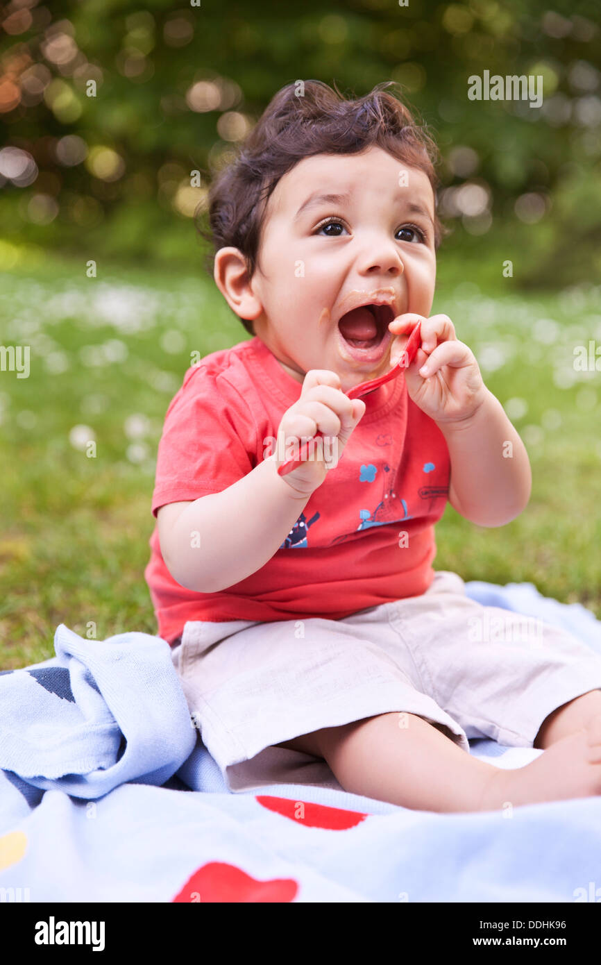Baby Boy holding spoon, looking up Banque D'Images