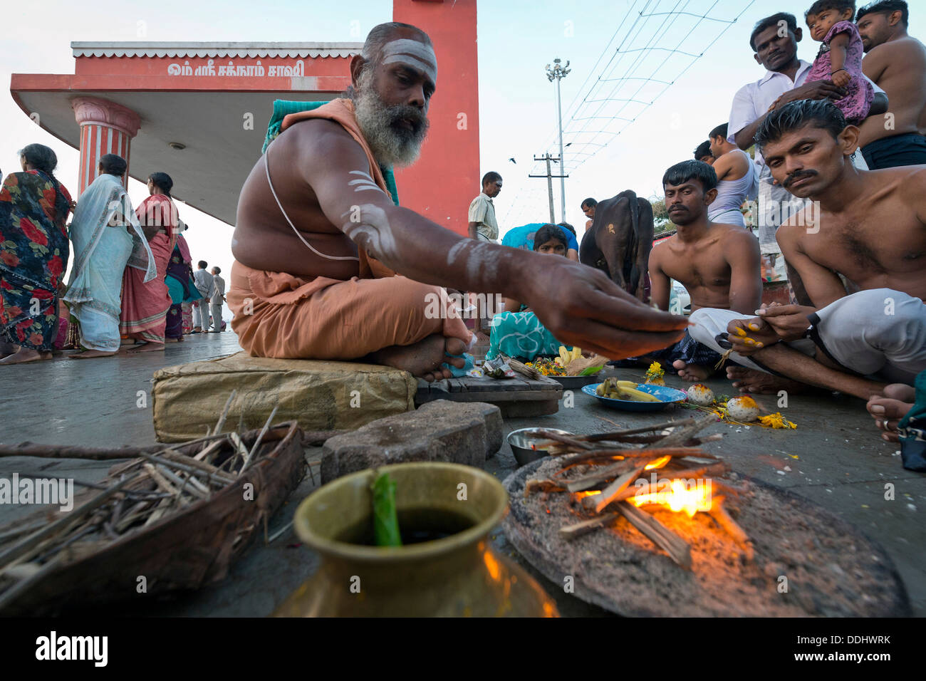 Prêtre hindou avec les pèlerins effectuant un rituel du feu à l'Agni Theertham Ghat Banque D'Images