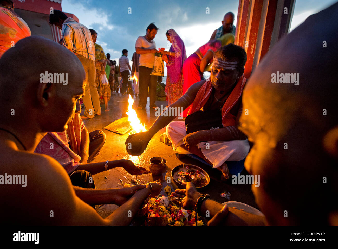 Prêtre hindou avec les pèlerins pendant un rituel du feu à l'Agni Theertham Ghat Banque D'Images