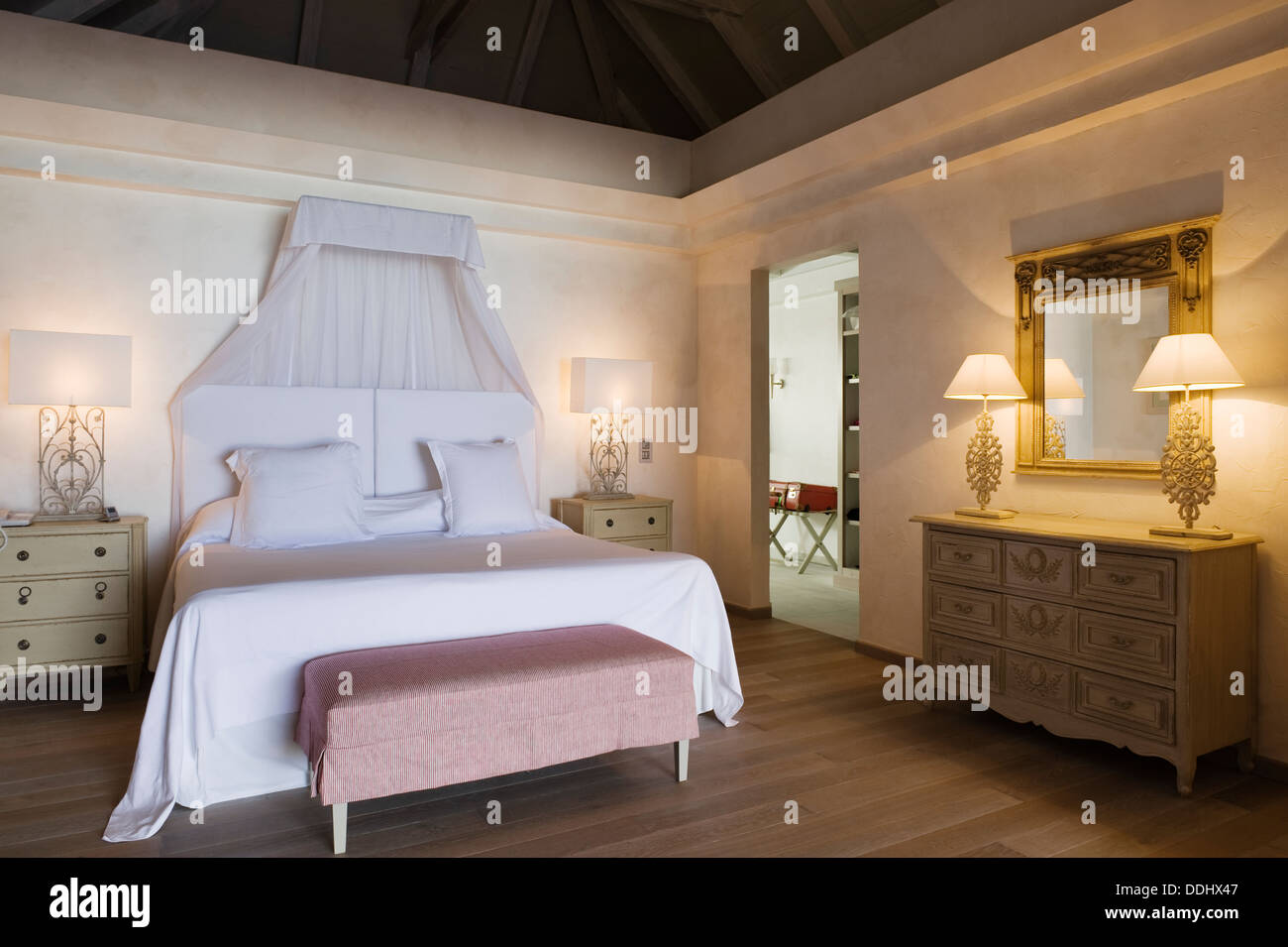 Des draps blancs sur un lit double dans la chambre avec banquette lit rembourré et plancher en bois Banque D'Images