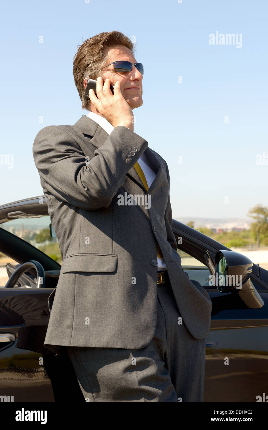 Businessman with cellphone près de la voiture Banque D'Images
